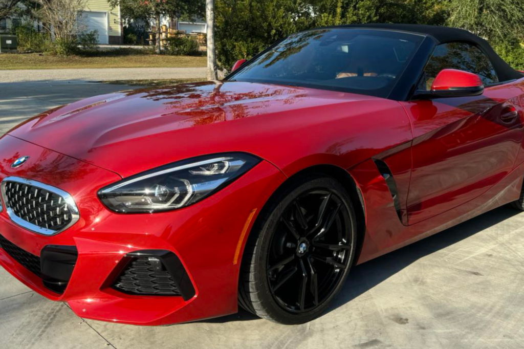 A red BMW Z4 roadster parked elegantly on a driveway, showcasing its sleek design and vibrant color.