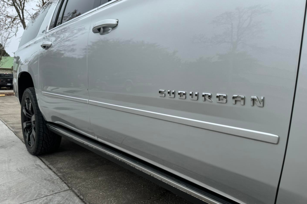 A white SUV parked on the street, showcasing its front end and sleek design against the urban backdrop.