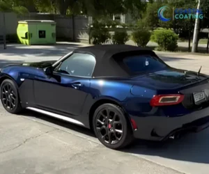 A close-up side view of the black sports car, highlighting the mirror-like reflections and clean.