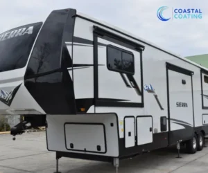 Angle shot of a white and black Sierra fifth-wheel travel trailer showing its side slide-out section and glossy finish