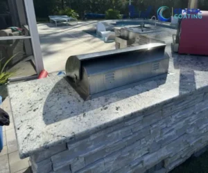 Close-up view of a stainless steel outdoor grill unit set into a light grey stone and granite island.